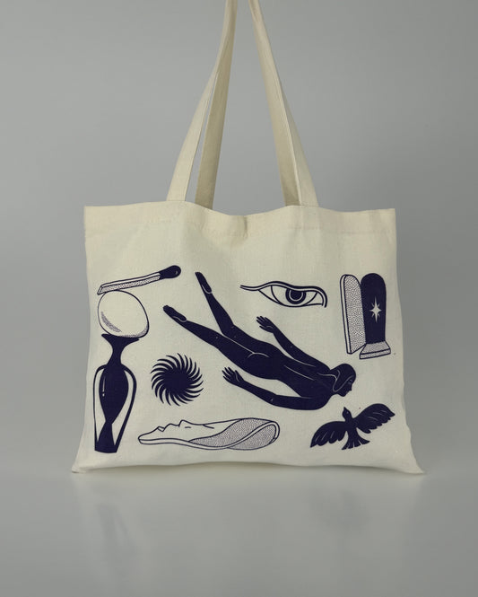 A canvas tote bag with a printed design featuring a diver, a soaring bird, a swirling star, an eye, a match, and an egg.